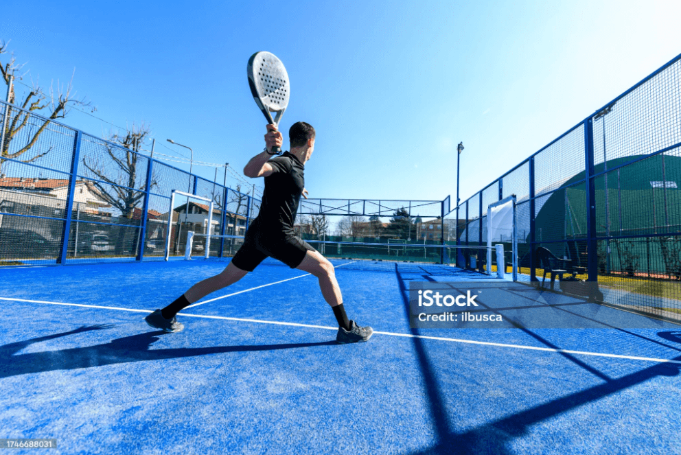 Jogador profissional de padel em posição de swing dinâmico em quadra azul